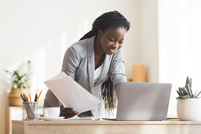 Femme en costume penchée au dessus d son bureau face à un ordinateur